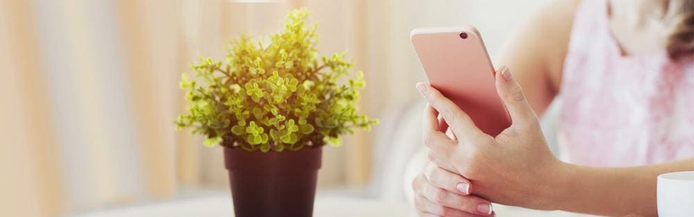 Naine suvises välikohvikus hoidmas roosat telefoni